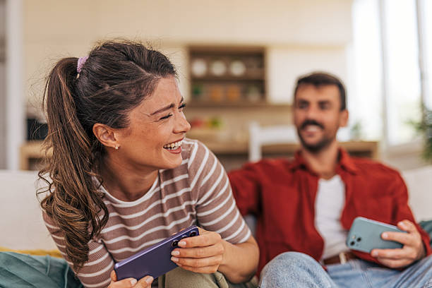istock Young couple relaxing on sofa, enjoying mobile games and laughing together 2222295347