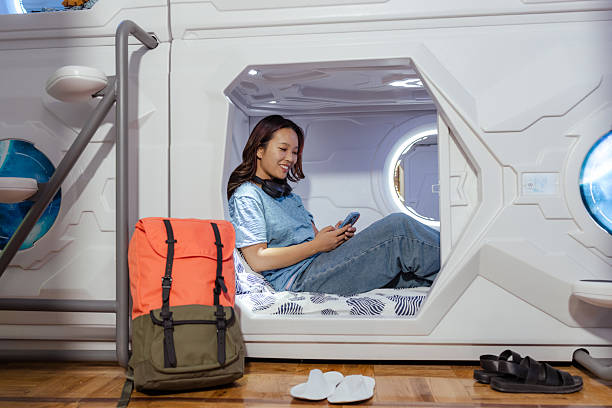 istock Young traveler relaxing in a modern capsule hostel room using a smartphone 2222299509