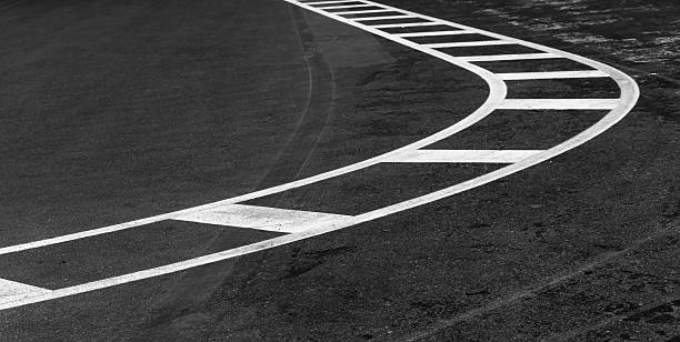 A monochrome depiction of a curved asphalt road adorned with dynamic white lane markings, emphasizing movement, guidance, and urban structure
