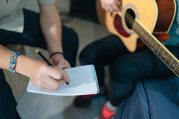 istock Musician composing music taking notes while playing acoustic guitar 2222302399