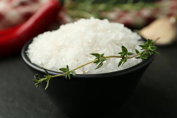 istock Sea salt and thyme in bowl on dark gray table, closeup 2222303281