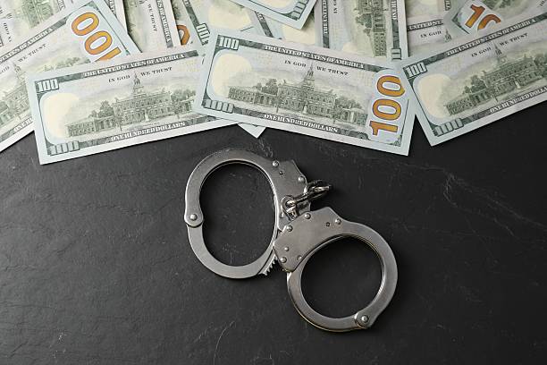 istock Corruption. Handcuffs and dollar banknotes on grey textured table, flat lay 2222305964