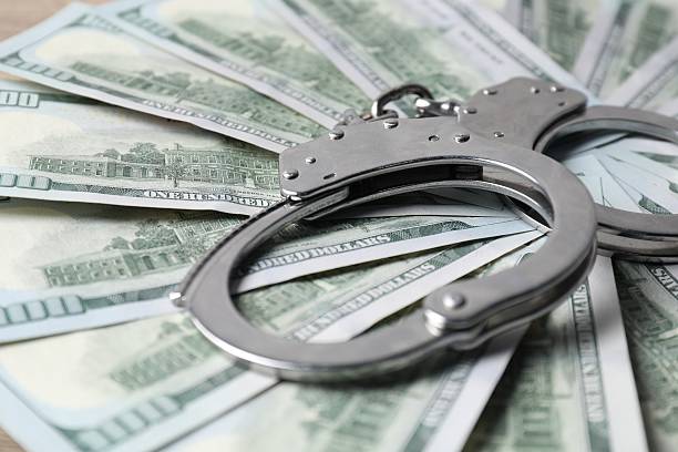 istock Corruption. Handcuffs and dollar banknotes on table, closeup 2222305994