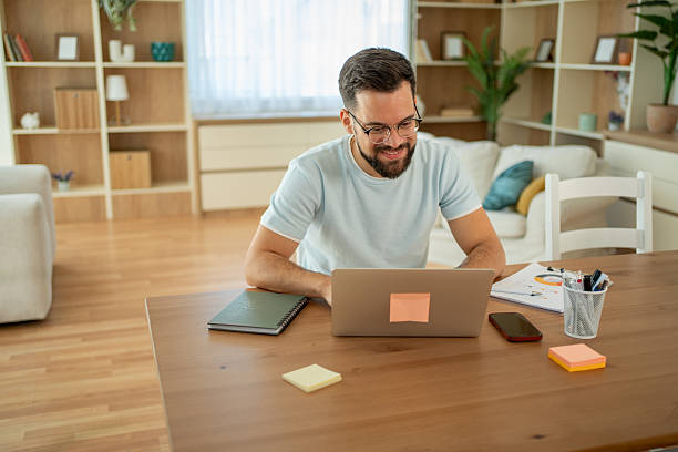Young businessman working from home using laptop and smiling