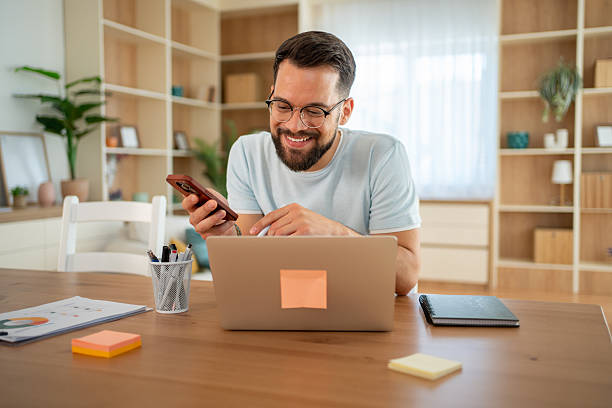 istock Young man working from home using laptop and smartphone 2222307089