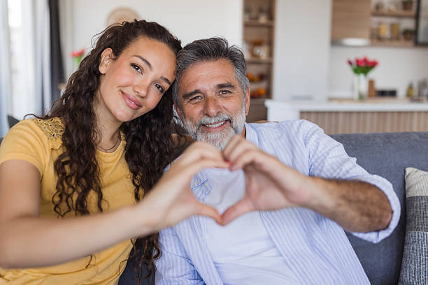 istock Father and daughter making heart shape with hands at home 2222311284