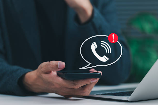 istock Phone Scam Alert and Warning Notification Concept. A person holding smartphone displaying call icon with alert symbol, representing scam call warnings, fraud awareness, digital communication threats, 2222316997