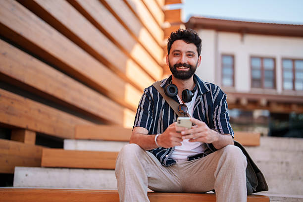 istock Strolling by Wooden Architecture: Man Using Mobile Phone Near Traditional Timber Building, looking at the camera. 2222321681