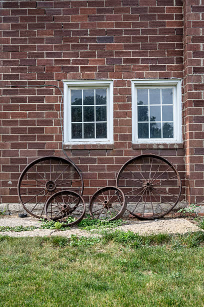 istock Old iron wheels in front of a brick barn 2222326957