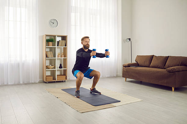 istock Concentrated athletic man trains squatting with dumbbells during workout at home. 2222330694