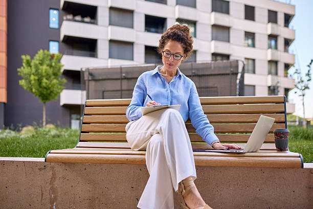 istock Businesswoman working with laptop and taking notes sitting on bench 2222331824