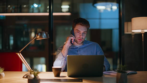 istock Hardworking employee talking mobile phone looking laptop at night office closeup 2222332299