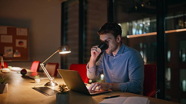 istock Overtime manager drinking coffee looking laptop screen at dark office. Tired man 2222333637