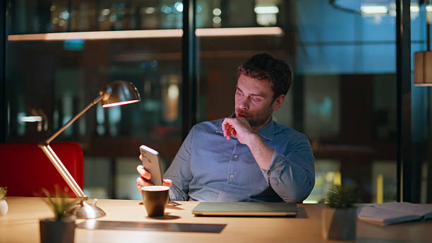 istock Unmotivated manager checking time phone sitting dark office with coffee closeup. 2222334701