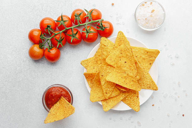 istock Crispy nacho chip in salsa bowl with plate of chips and fresh tomatoes 2222338476