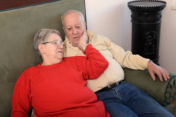 istock Senior couple sitting on the couch at home 2222342873
