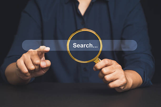 istock Man holding magnifying glass over search bar interface, concept of internet browsing or SEO. 2222350631