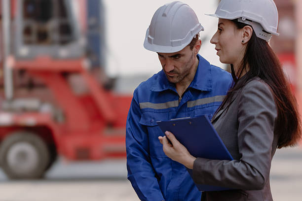 istock Industrial engineer woman working at import export distribution port. Diverse people work together 2222352840