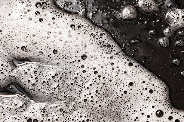 istock Foam bubbles on dark surface closeup. Abstract texture of soapy liquid. Clean water with foam on black background. 2222357477