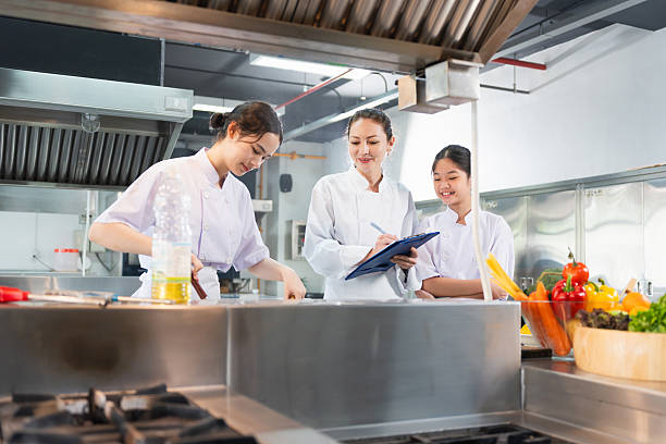 istock Culinary Team Collaborating and Learning in Restaurant Kitchen, Female Chefs Preparing Food and Taking Notes in a Modern Kitchen, Professional Chefs Working Together in a Busy Commercial Kitchen 2222358982