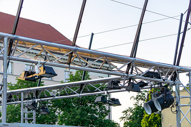 istock Professional stage lighting mounted on an aluminum truss structure, set up outdoors with buildings and trees in the background. Preparation for an open-air event. 2222362103