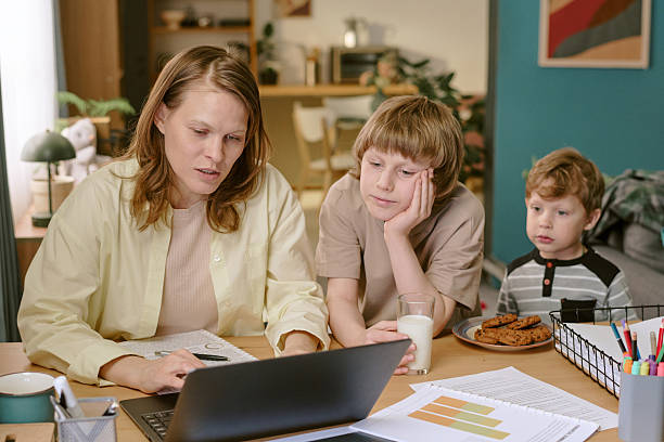 istock Middle Aged Woman Working Remotely While Supervising Two Children 2222369131
