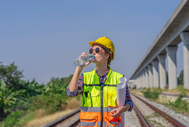istock railway engineer or construction worker in hardhat and safety vest,thirsty in the harsh sunlight,drinking water while working outside at railway 2222374461