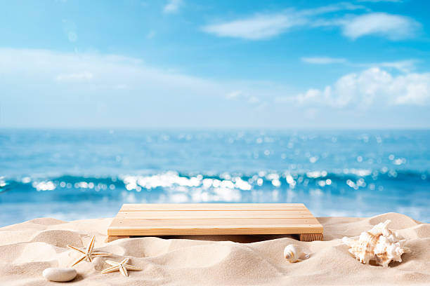 istock Podium with tropical shells on sandy beach for product presentation over blurred summer sea background 2222379688