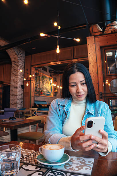 istock Woman using smartphone and drinking cappuccino in a cafe 2222381397