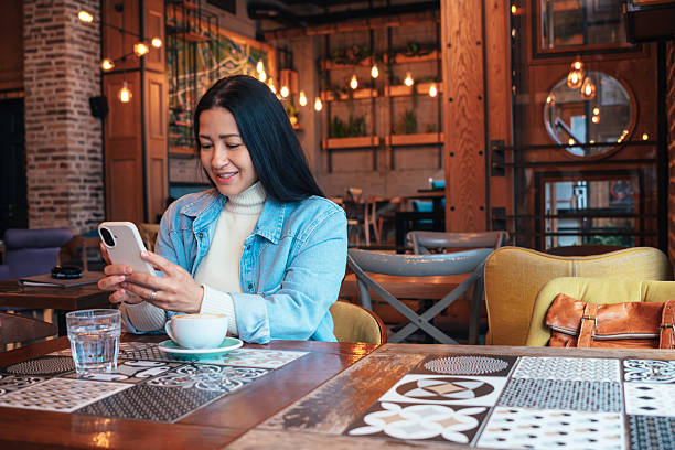 istock Woman using smartphone and drinking cappuccino in a cafe 2222381402