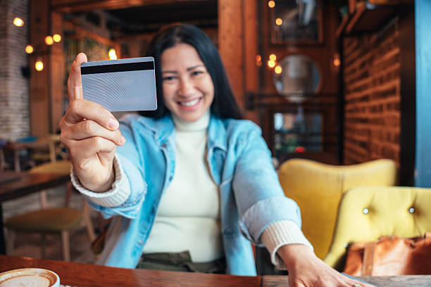 istock Young woman showing credit card while sitting in cafe 2222381668