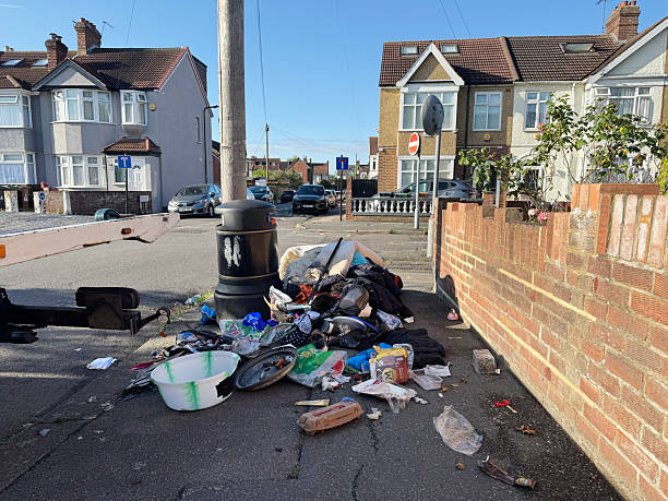Pile of household waste left by a litter bin on a street corner in Chingford north London. June 2025
