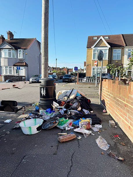 Pile of household waste left by a litter bin on a street corner in Chingford north London. June 2025