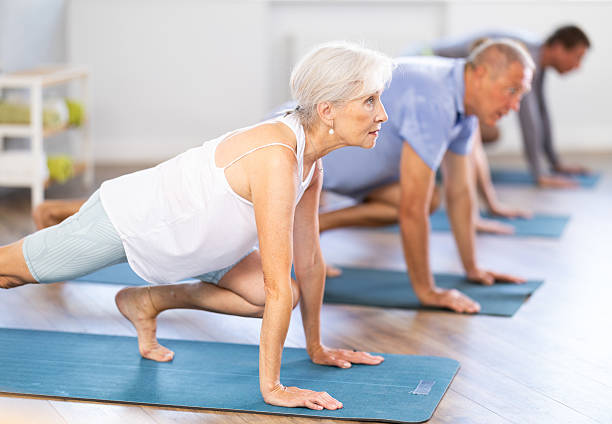 istock Mature female participant working out practice  warrior pose, virabhadrasana with group 2222389881