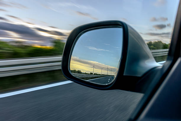 istock Car side mirror. Wind turbines on horizon. Speed and sustainability 2222391062