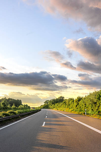 istock Empty road under blue sky. Sunset highway. Forest landscape 2222391070