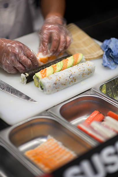 istock Chef Preparing Fresh Sushi Rolls on Cutting Board in a Professional Kitchen 2222391111