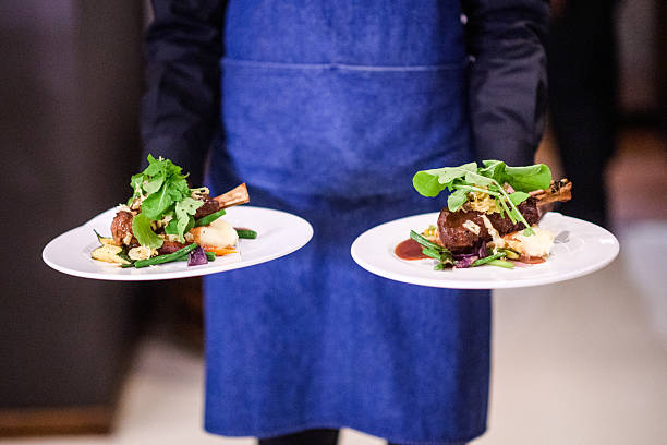 istock Waiter serving gourmet dishes elegantly styled on white plates in a high-end setting 2222391166