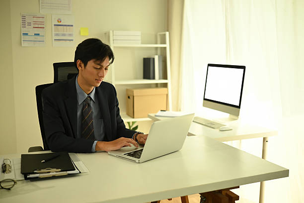 istock Confident young businessman working on a laptop in a bright, modern office 2222393274