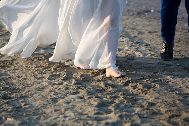 Newlyweds walking barefoot on the beach during sunset, enjoying their first moments as husband and wife