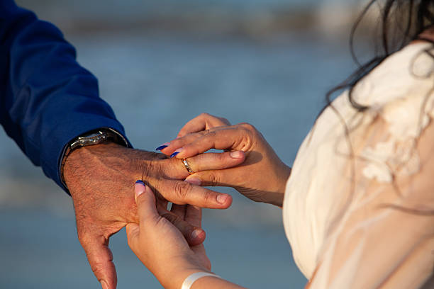 istock Bride placing wedding ring on groom's finger during beach ceremony 2222401904