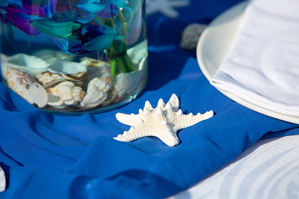 Elegant beach-themed table setting with starfish, seashells, and blue orchids