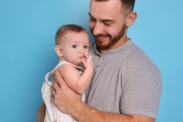 istock Father with his cute baby on light blue background 2222404227