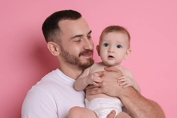 istock Father with his cute baby on pink background 2222404236