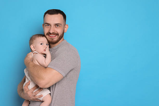 istock Father with his cute baby on light blue background, space for text 2222404259