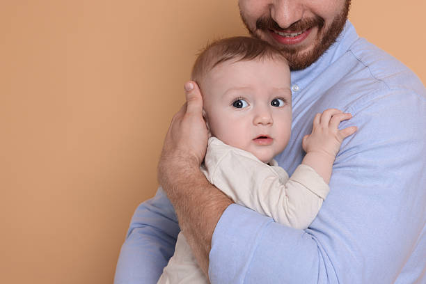 istock Father with his cute baby on beige background, space for text 2222404271