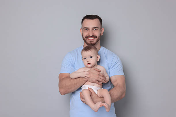 istock Father with his cute baby on grey background 2222404297