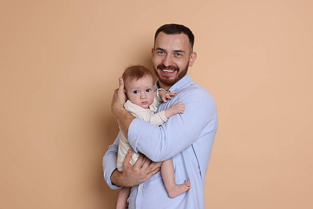 istock Father with his cute baby on beige background 2222404298