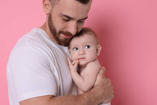 istock Father with his cute baby on pink background, space for text 2222404299