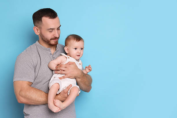 istock Father with his cute baby on light blue background, space for text 2222404312